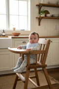 Baby in farmhouse kitchen high chair with blue striped bib