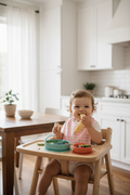 Baby in high chair with pink gingham bib