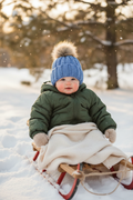 Baby in sled wearing blue beanie