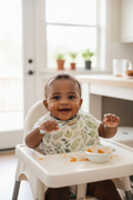 Baby with darker skin in high chair with sage botanical bib