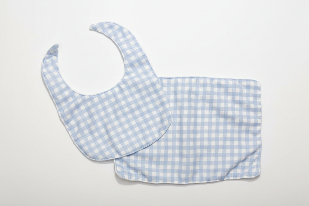 Professional flat lay of light blue gingham bib and burp cloth set