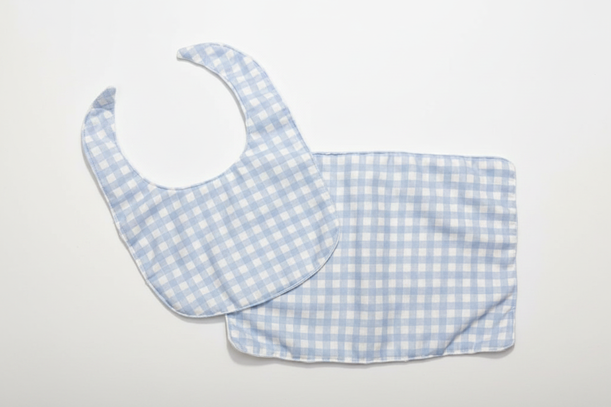 Professional flat lay of light blue gingham bib and burp cloth set