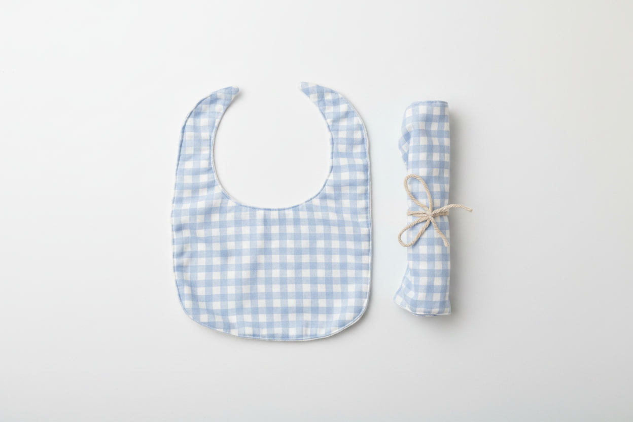 Professional flat lay of light blue gingham bib and rolled burp cloth set